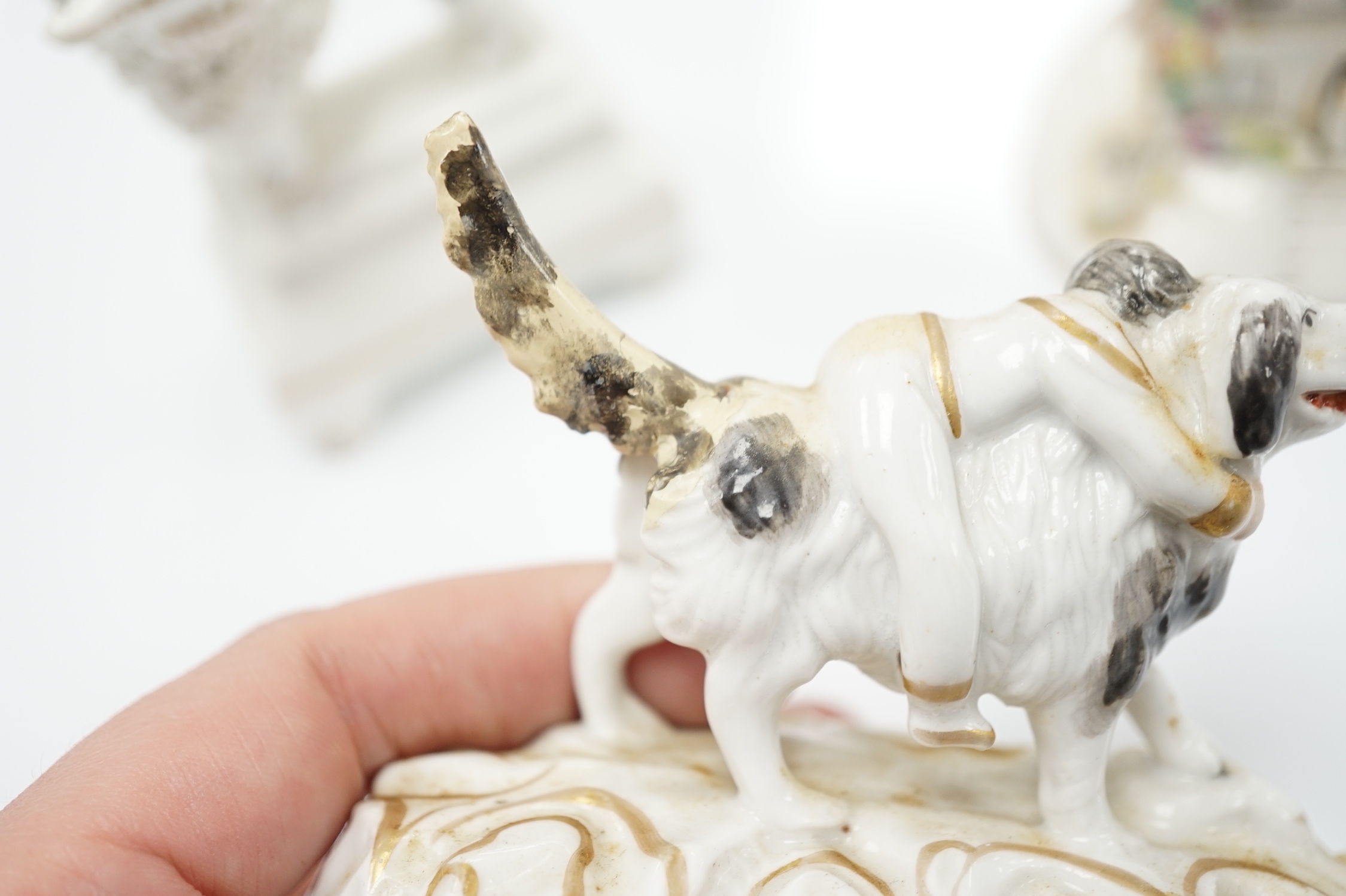 Three Staffordshire porcelain dog figures, c.1830-50, comprising a boy clinging to the back of a spaniel, a model of a poodle with a bird in its mouth and a model of a cottage with a small dog in the doorway, tallest 9cm